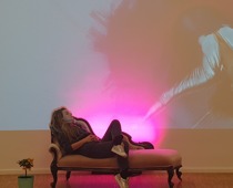 Bogi Nagy: „Bogi auf der Chaisselongue vor der Projektion eines Performance-Videos © Ida Hinterholzinger“